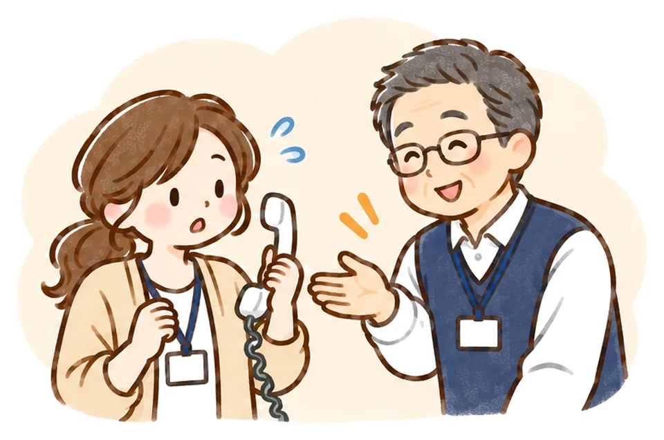 受話器を耳から少し離して困った顔のケアマネに、管理者が代わると手を差し出している